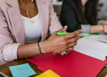 woman in white shirt holding green pen