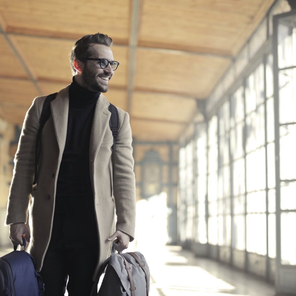 man in brown robe carrying bag smiling