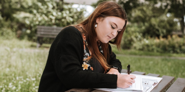 concentrated woman writing notes in papers in park