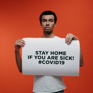 man in white crew neck t shirt holding stay at home sign