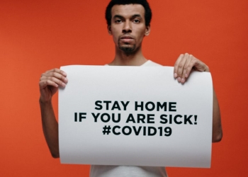 man in white crew neck t shirt holding stay at home sign