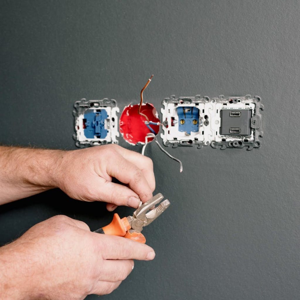 an electrician using pliers to repair the ac power plugs and sockets
