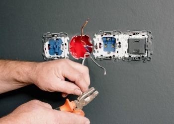 an electrician using pliers to repair the ac power plugs and sockets