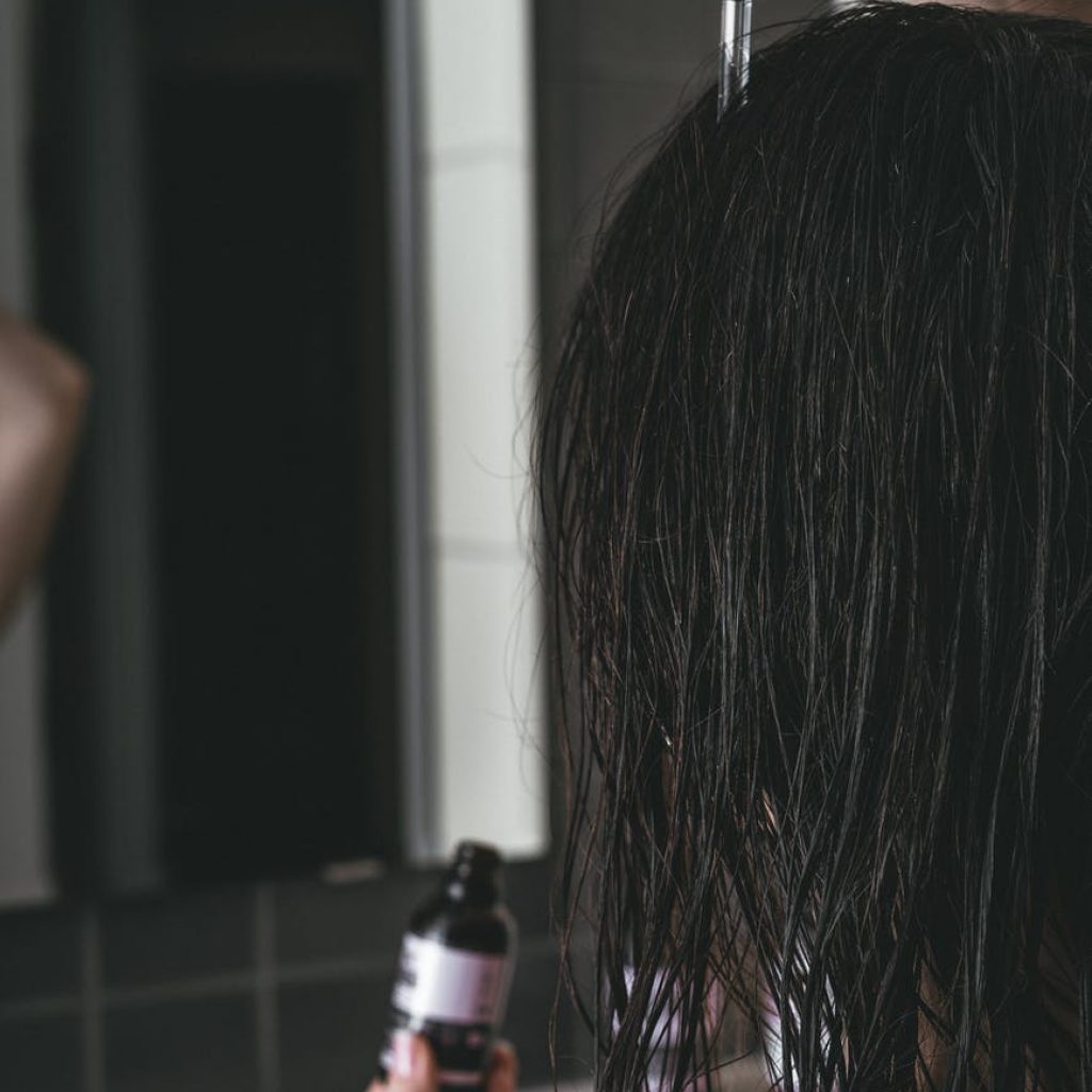 woman putting a product on her hair