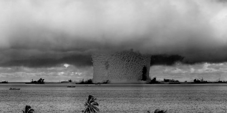 grayscale photo of explosion on the beach