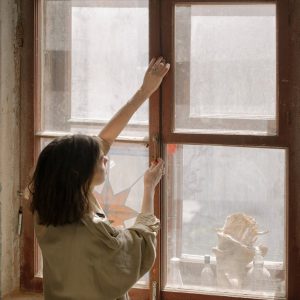 woman in white shirt looking out the window