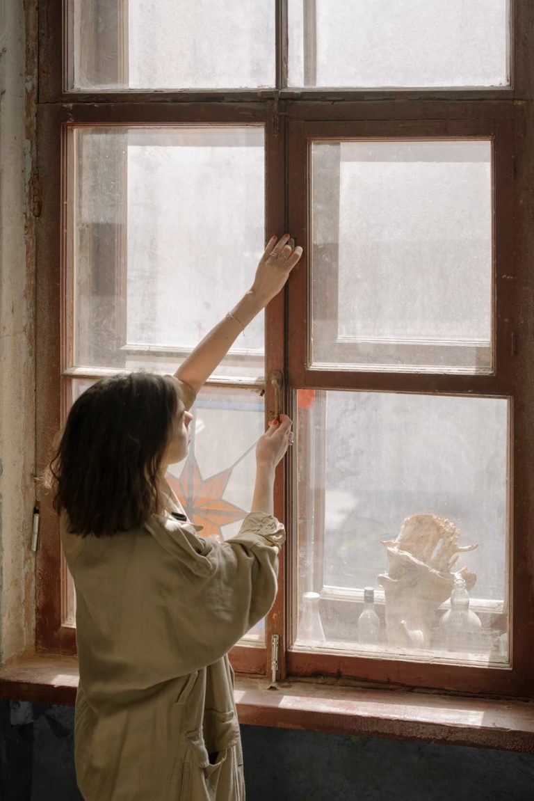 woman in white shirt looking out the window