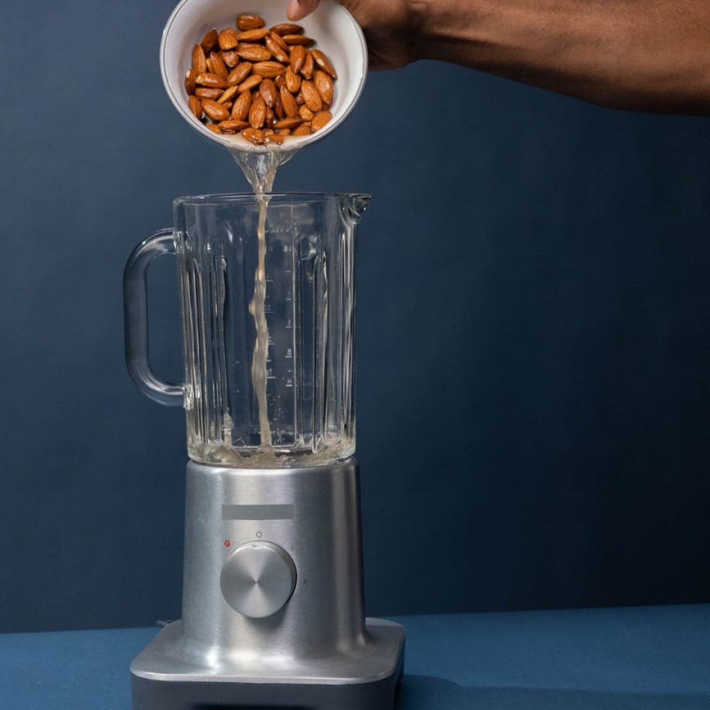 pouring of pecan nuts with liquid on a blender