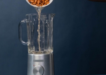 pouring of pecan nuts with liquid on a blender