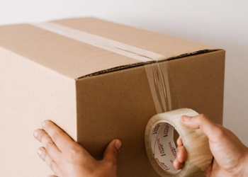 crop man sealing carton box with tape