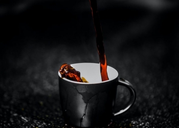 brown liquid pouring on black and white ceramic mug selective color photography