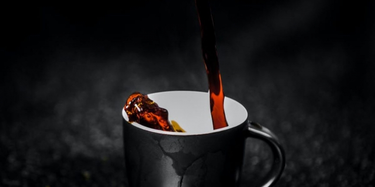 brown liquid pouring on black and white ceramic mug selective color photography