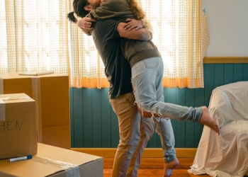cheerful couple hugging and unpacking carton boxes