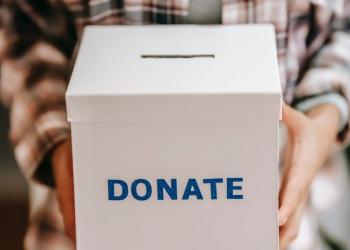 crop anonymous person showing donation box