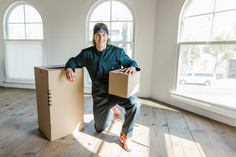 man in blue coverall posing between carton boxes