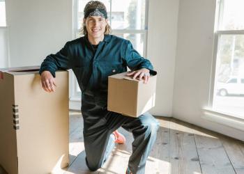 man in blue coverall posing between carton boxes