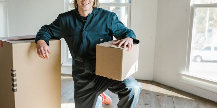 man in blue coverall posing between carton boxes