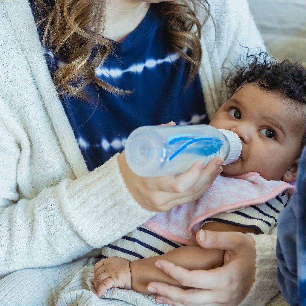 mother feeding black baby from bottle