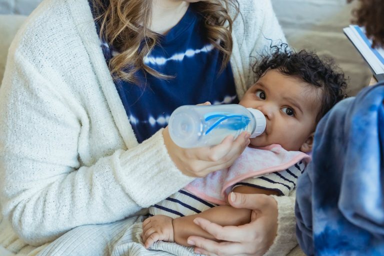 mother feeding black baby from bottle