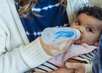 mother feeding black baby from bottle