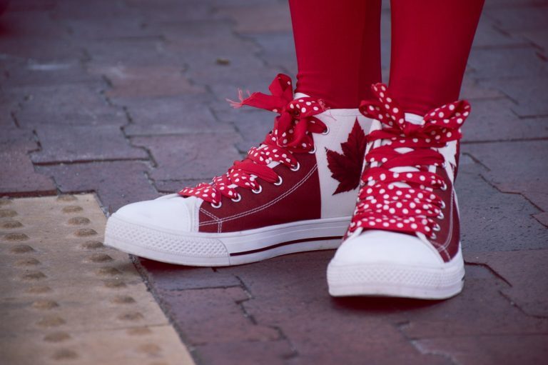 closeup photo of person wearing white and red maple leaf printed lace up sneakers