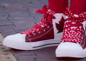 closeup photo of person wearing white and red maple leaf printed lace up sneakers