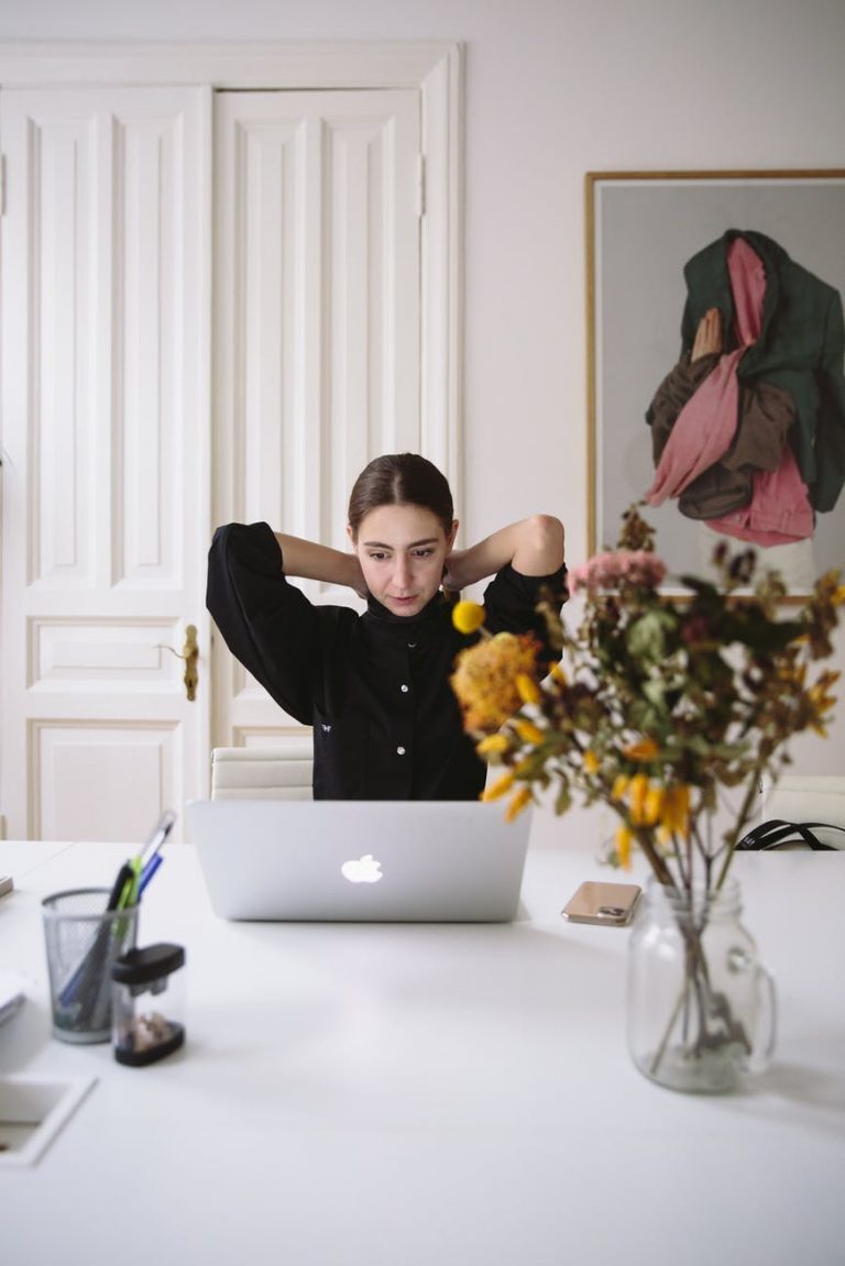 woman in black blouse sitting in front of silver laptop