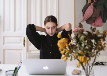 woman in black blouse sitting in front of silver laptop