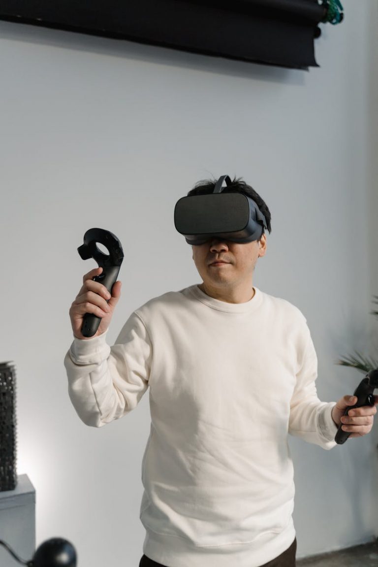 man in white sweatshirt wearing a virtual reality headset with game controllers