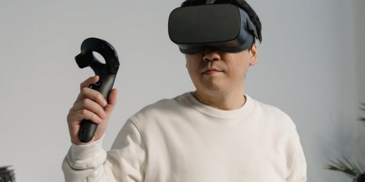 man in white sweatshirt wearing a virtual reality headset with game controllers