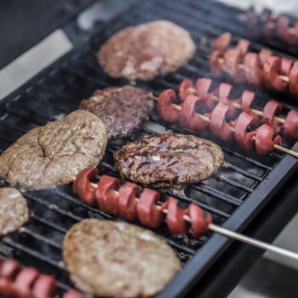 steaks and skewered sausages on grill