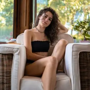woman with wavy hair resting in cozy armchair
