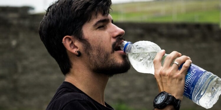 man wearing black shirt drinking water