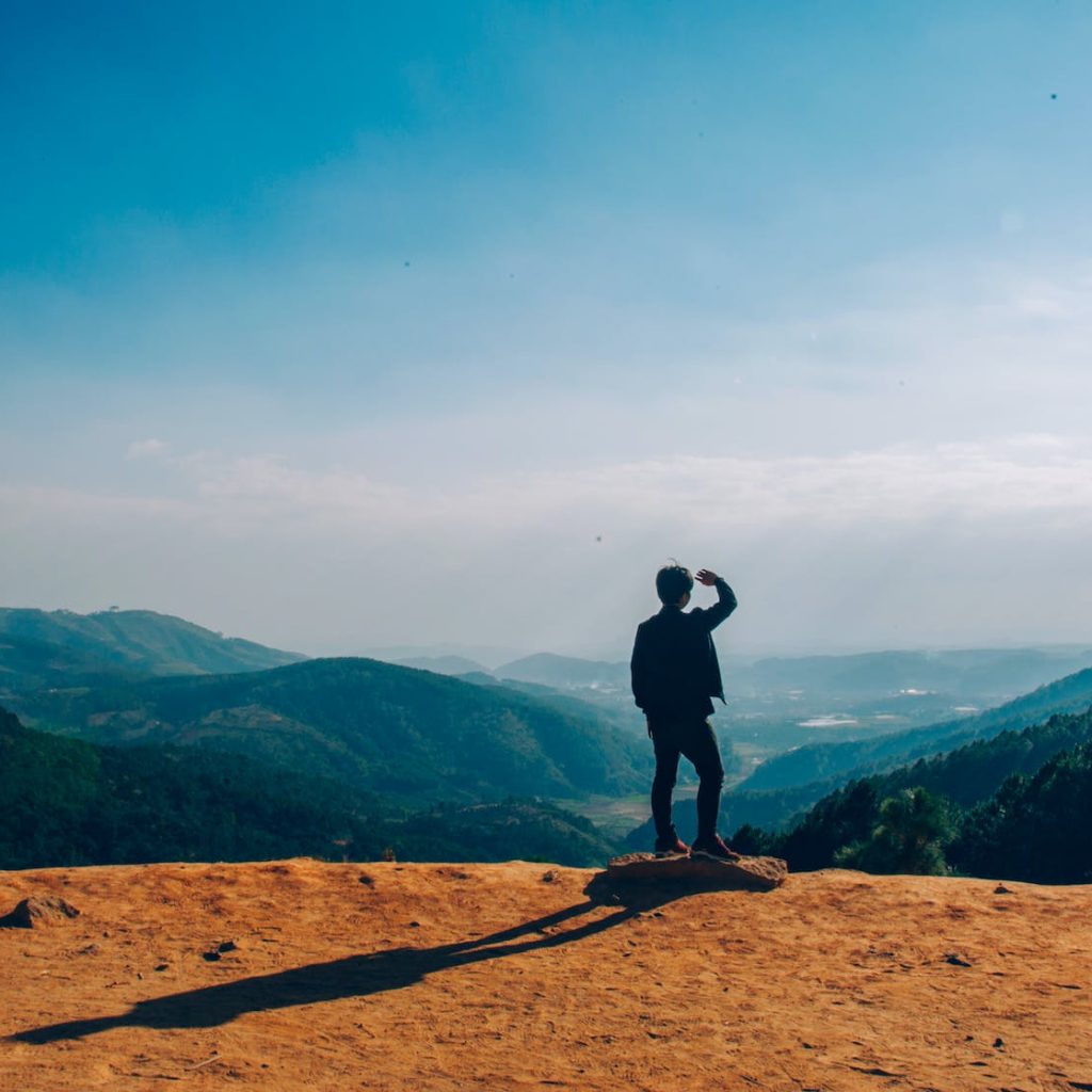 silhouette of man standing on mountain cliff