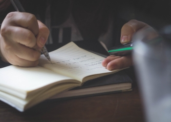person writing while using phone