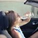 adult female drinking water in convertible car in city