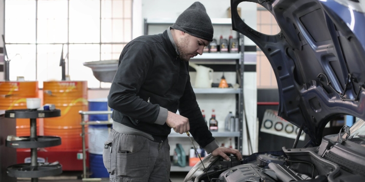 photo of man inspecting car engine