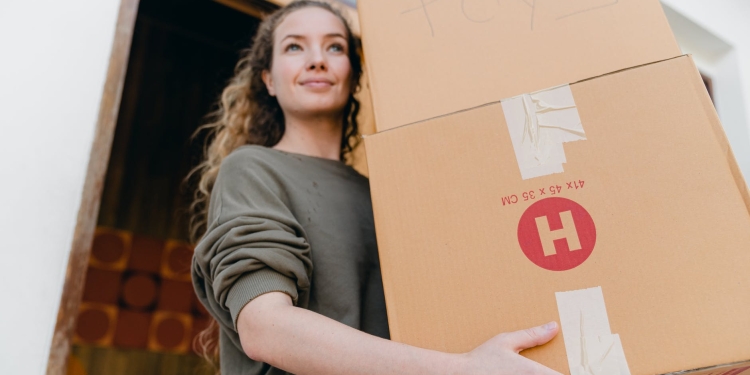 young woman with boxes while moving out of old home