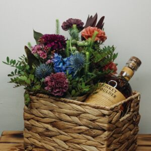 bouquet of flowers with whisky bottle in woven basket