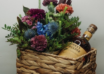 bouquet of flowers with whisky bottle in woven basket