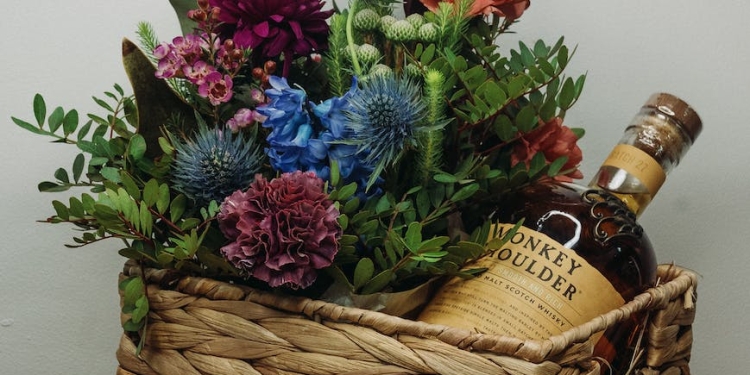 bouquet of flowers with whisky bottle in woven basket