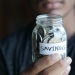 close up shot of a person holding a jar with coins
