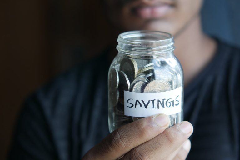 close up shot of a person holding a jar with coins