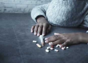 close up photo of person lying beside a syringe and tablets