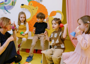 children with her students holding different color bells