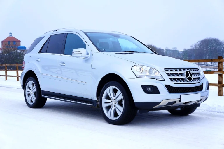 white mercedes benz suv parked beside brown wooden fence
