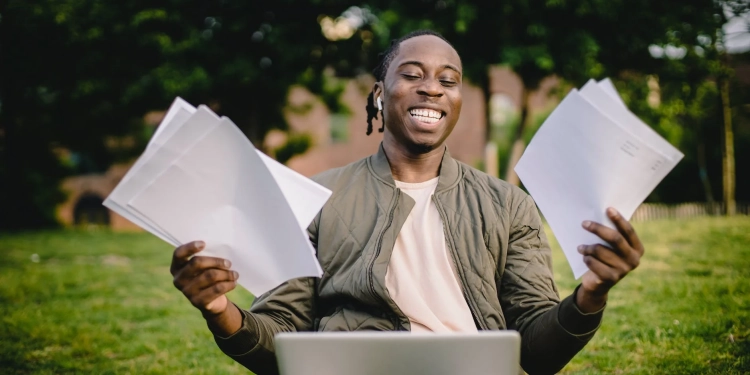 student with documents and laptop happy about getting into university