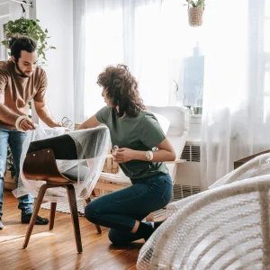 couple wrapping a chair with plastic