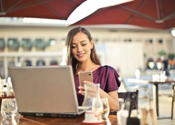 woman wearing purple shirt holding smartphone white sitting on chair