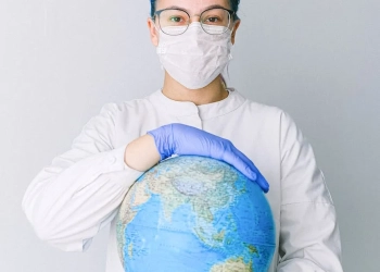 person with a face mask and latex gloves holding a globe